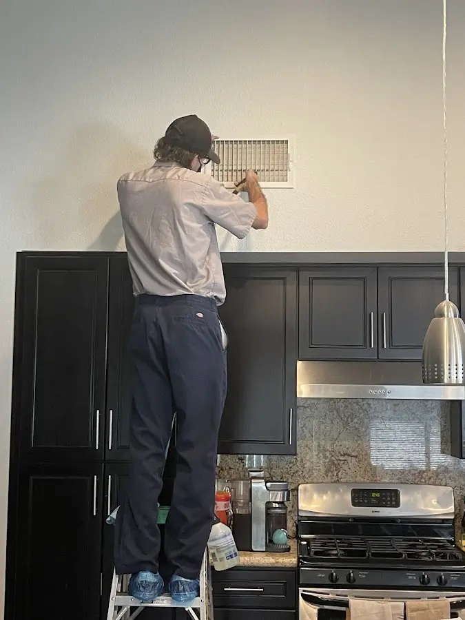Technician inspecting an air vent during HVAC service in Mayflower Village